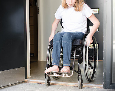Mädchen in Rollstuhl überrollt niedrige Türschwelle