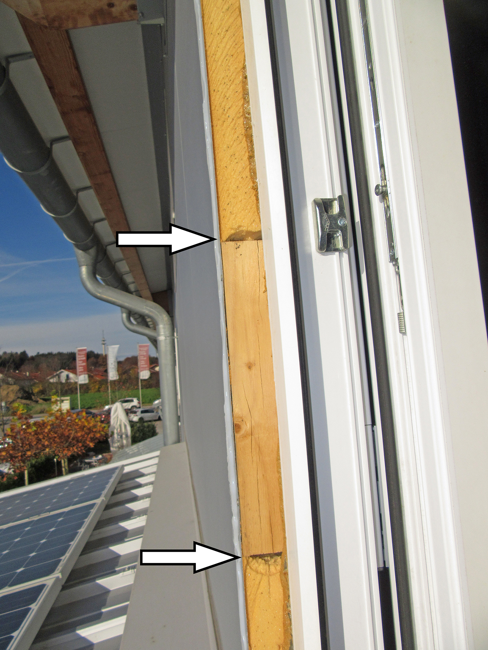 Das Foto zeigt ein durch den Fensterlieferanten abschnittsweise ins Paneel eingefügtes Holzteil (s. Pfeile) für die Anbindung der Fenster. Das Paneel ist nicht in der Lage, Lasten aufzunehmen.