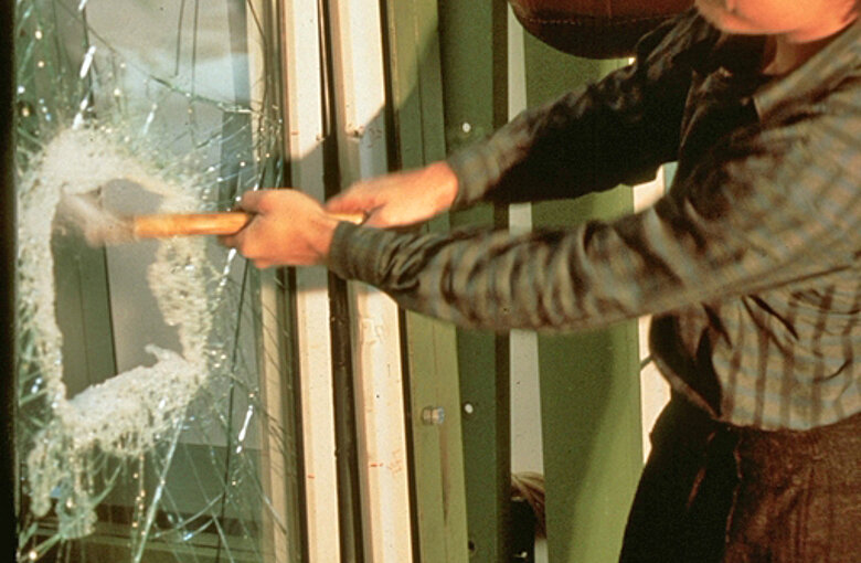 Man smashes through a pane of glass with a hammer