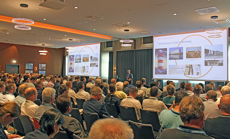 Das Foto zeigt einen Blick in den Veranstaltungssaal über das Publikum bei der Eröffnung durch Christian Kehrer. (Quelle: ift Rosenheim)