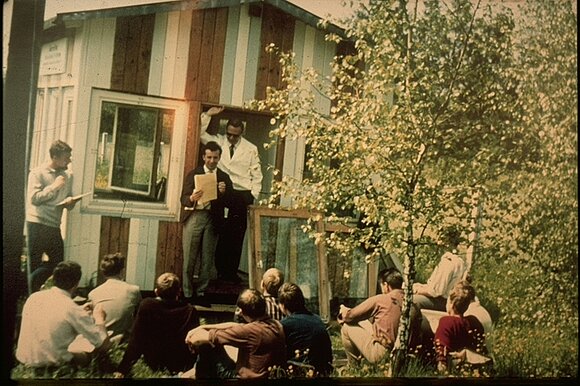 Das alte Foto zeigt einen Vortrag über Fenster vor Studenten draußen im Grünen.