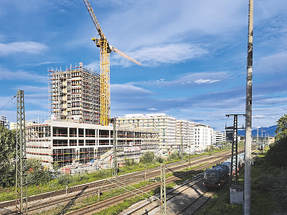 Das FOto zeigt eine größere Baustelle direkt neben den Bahngleisen in der Stadt Rosenheim.