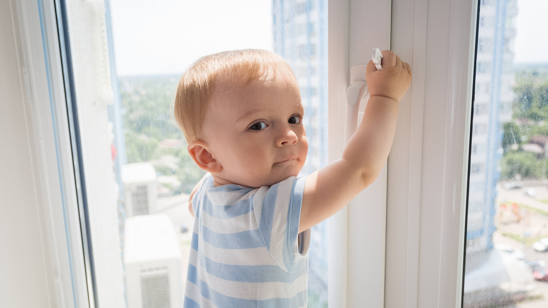 Kleines Kind hält sich am Fenster fest