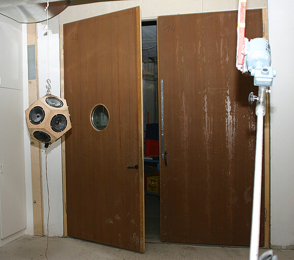Das Foto zeigt eine zweiflügelige braune Holztür die gerade auf Schall geprüft wird.