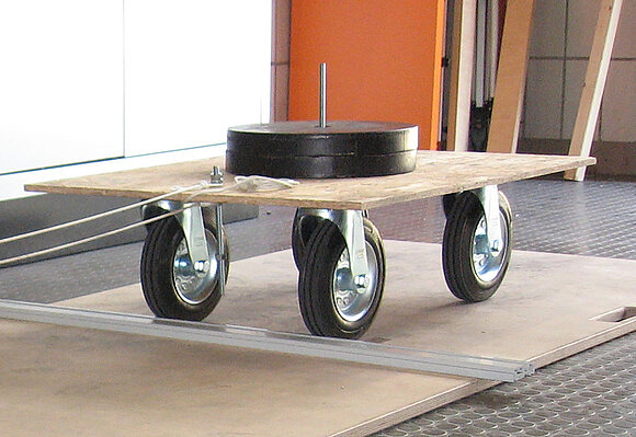 Kleiner Rollwagen mit Gewicht darauf zur Ermittlung der Überrollbarkeit von Schwellen.