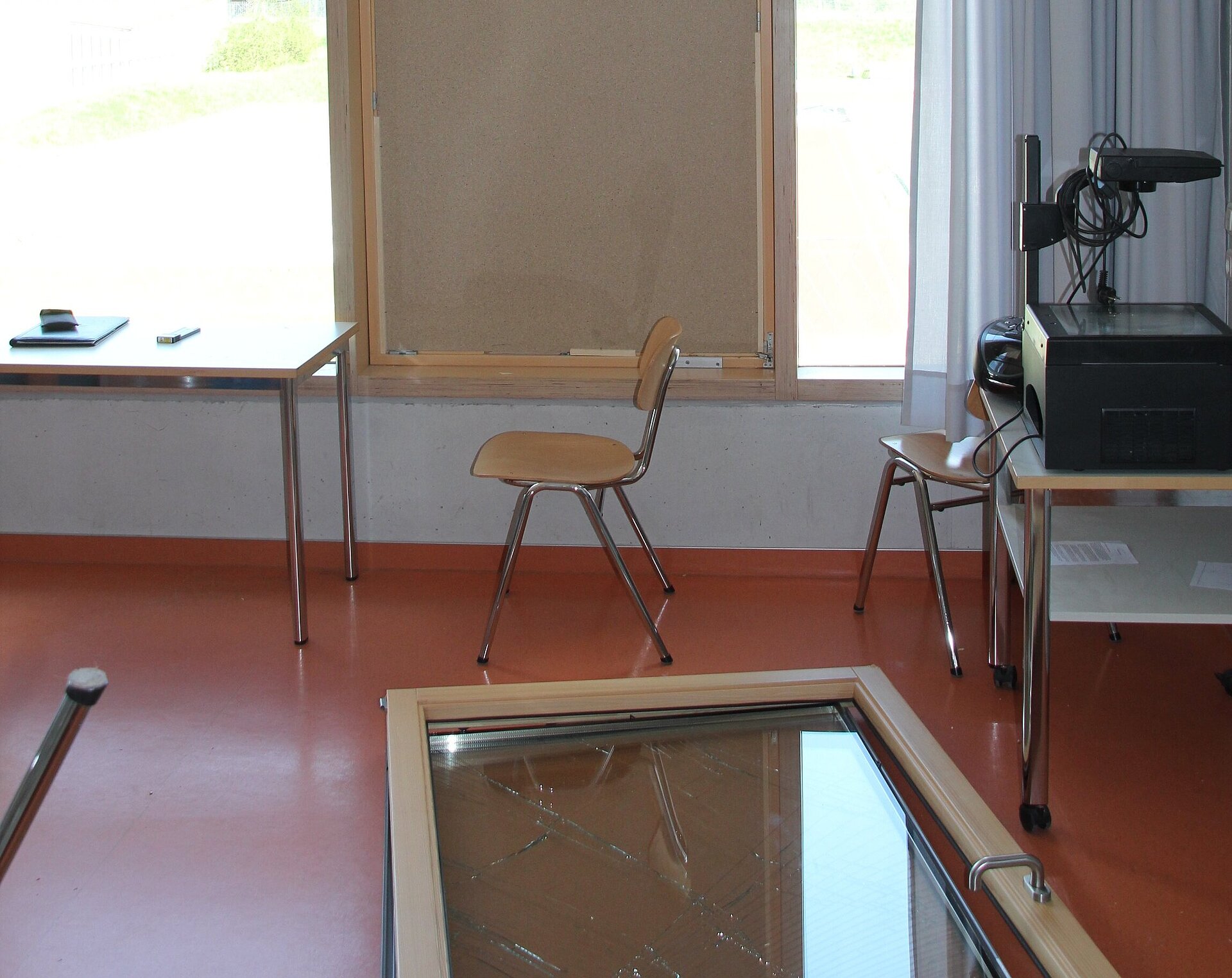 Das Foto zeigt ein kaputtes Fenster an einer Schule, das provisorisch zugemacht wurde, da der Flügel herausgefallen ist