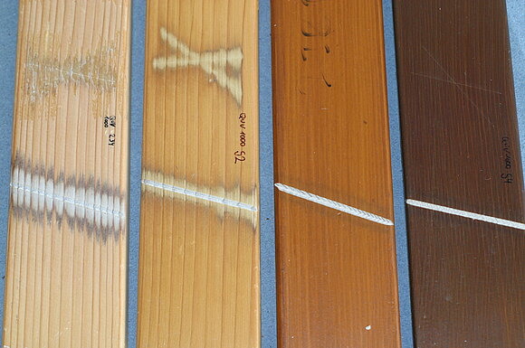 Das Foto zeigt vier beschichtete Holzproben nach künstlicher Bewitterung (EN 927-6).