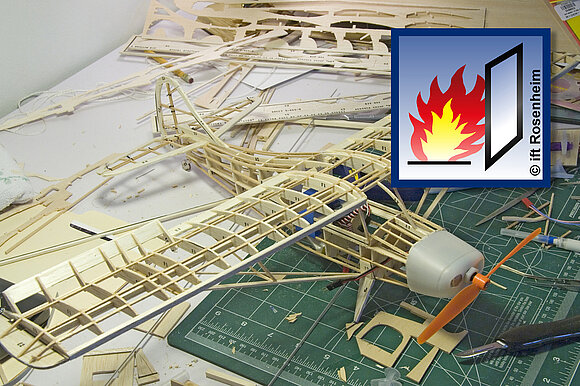 Auf den Foto ist ein Modellflugzeug abgebildet mit Piktogramm Brandschutz des ift Rosenheim.