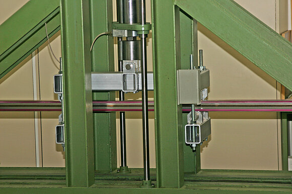 Das Foto zeigt ein Aluminium-Fensterprofil, das in eine Prüfeinrichtung für Biegeversuche eingespannt ist. 